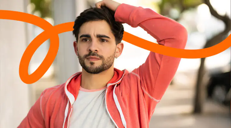 Portrait of a man with a trimmed beard in a coral hoodie, outdoors, with an orange curved branding swoosh across the image.