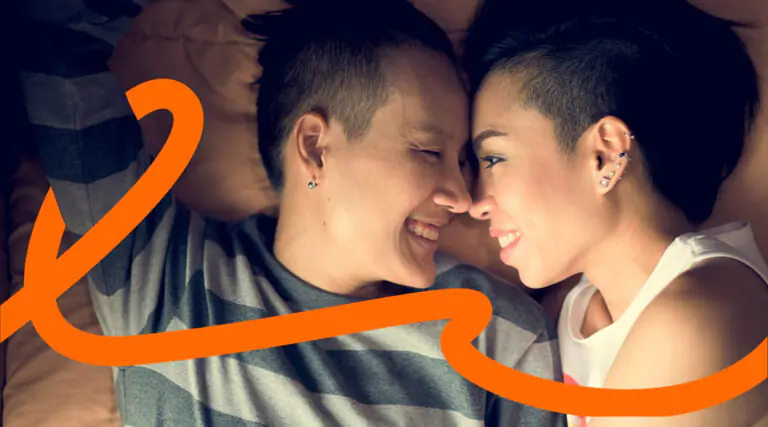 Two people lying close together on a bed, noses touching and smiling at each other, with an orange decorative swirl across the scene.